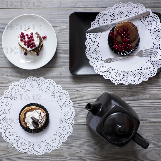 Teapot and plates of dessert on lace doilies