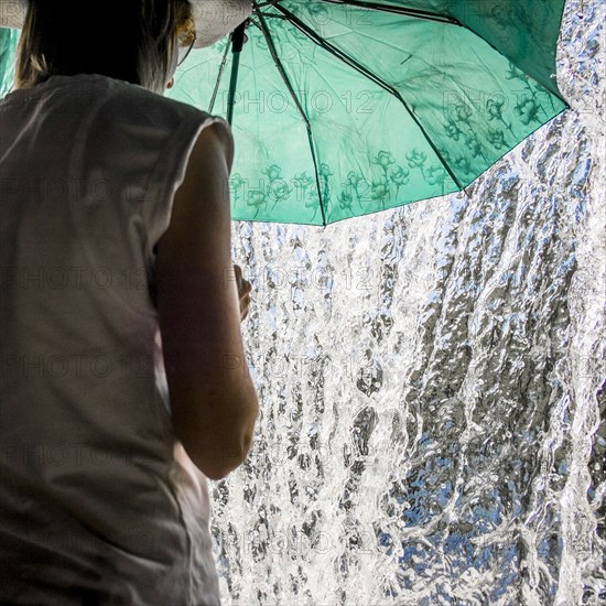 Caucasian woman holding umbrella near splashing water