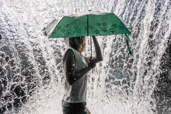 Caucasian woman holding umbrella near splashing water