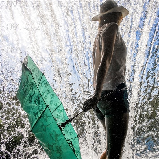 Caucasian woman holding umbrella near splashing water