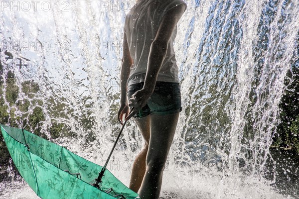 Caucasian woman holding umbrella near splashing water