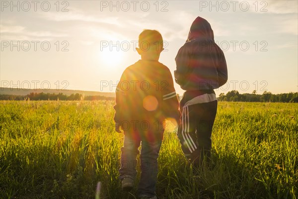 Mari boys walking in field at sunset