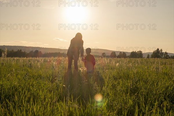 Woman and son standing in field at sunset