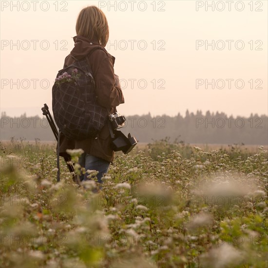 Caucasian photographer standing in field of flowers