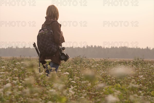 Caucasian photographer standing in field of flowers
