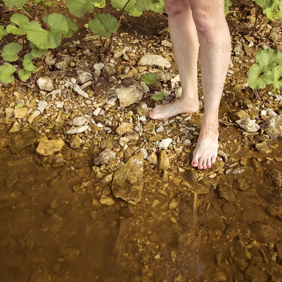 Legs of Caucasian woman standing on shore of lake