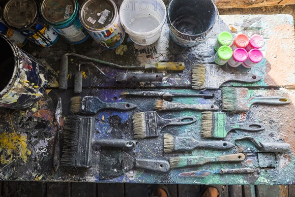 Used paintbrushes and paint cans on table