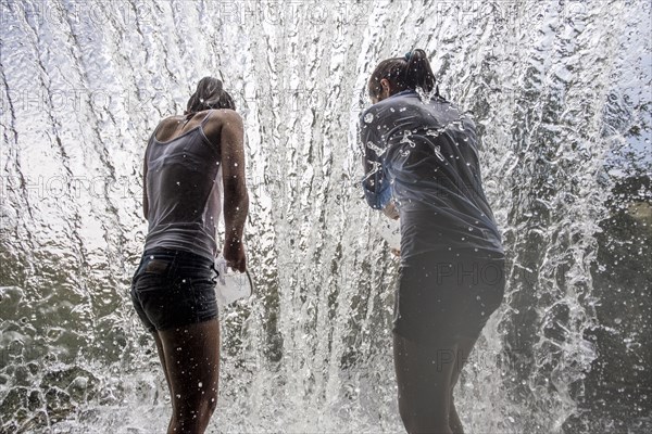 Caucasian mother and daughter standing in waterfall