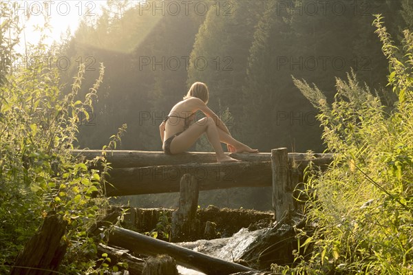 Caucasian woman sitting on log over waterfalls