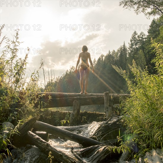 Caucasian woman standing on log over waterfalls
