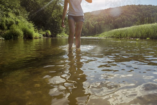 Caucasian woman wading in river