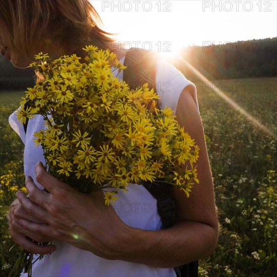 Caucasian woman holding flowers in sunny field