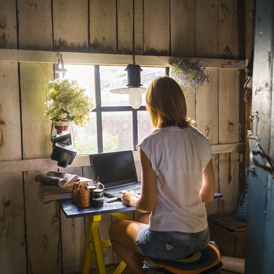 Caucasian woman using laptop near rustic window