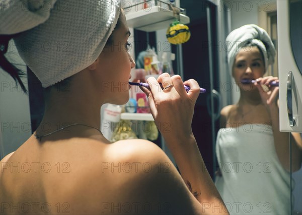 Caucasian woman brushing teeth in mirror