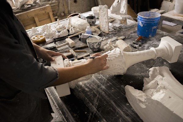 Hands of Caucasian sculptor carving plaster piece