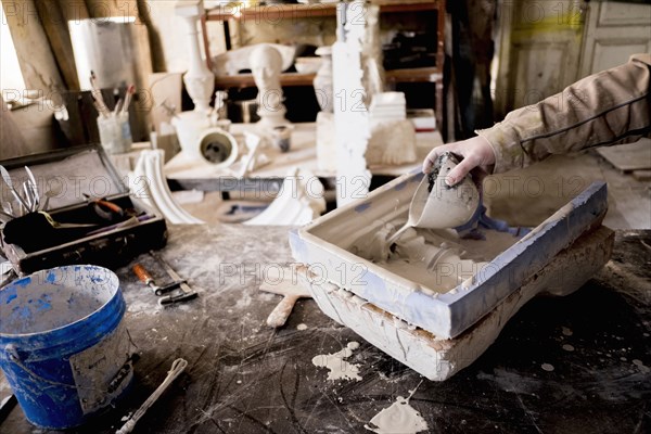 Caucasian artist pouring plaster into mold