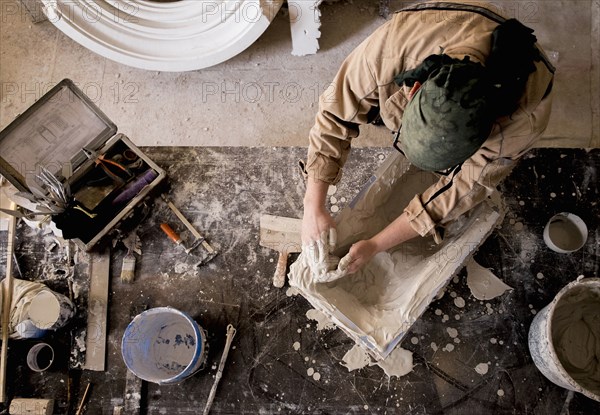 Caucasian artist spreading plaster into mold with hands