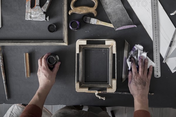 Hands of Caucasian artist staining picture frame