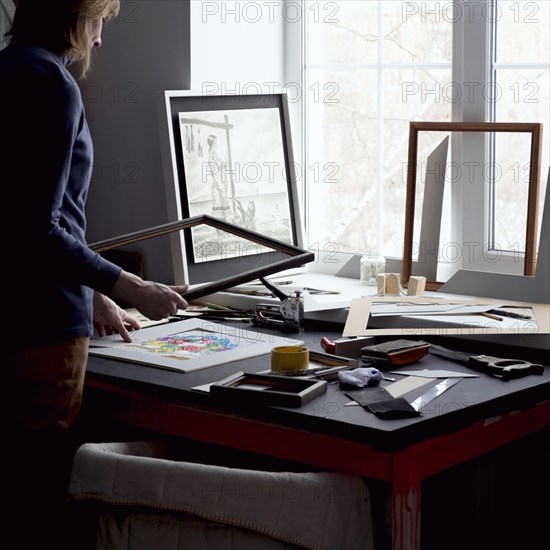 Caucasian woman holding picture frame at table