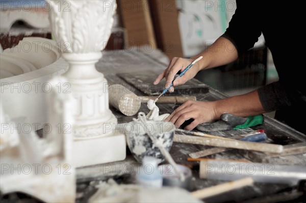 Caucasian artist sculpting with tool