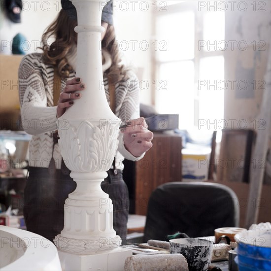 Caucasian artist sculpting with tool