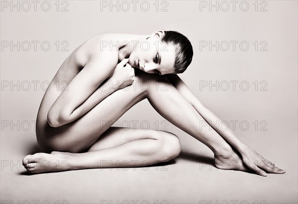 Portrait of naked Caucasian woman sitting on floor