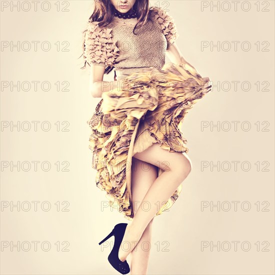 Caucasian woman wearing ruffled skirt standing on one leg