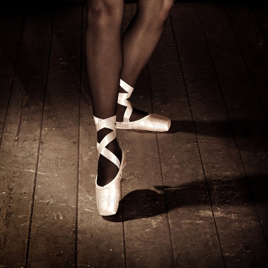 Legs of Caucasian ballerina standing on wooden floor