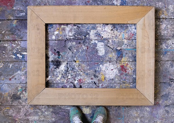 Feet standing over picture frame on wooden floor