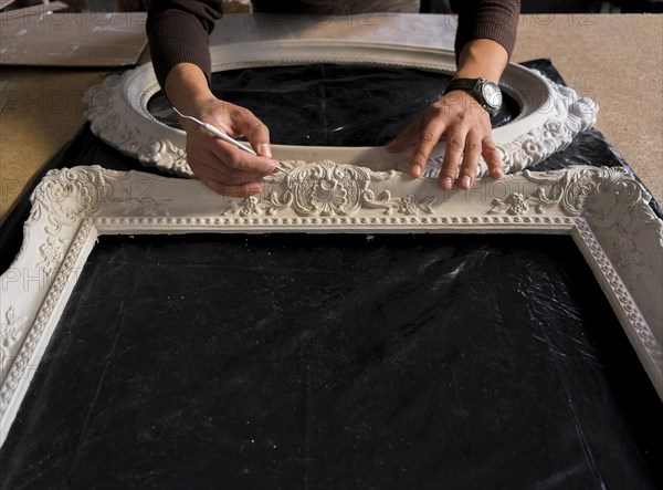 Hands of Caucasian man detailing picture frame