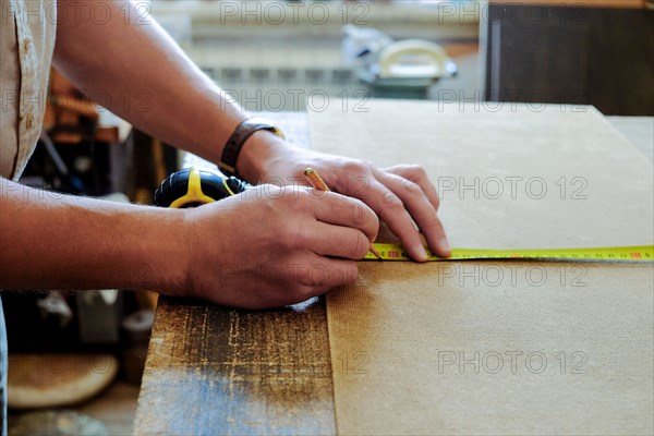 Hands of Caucasian man using pencil and measuring tape