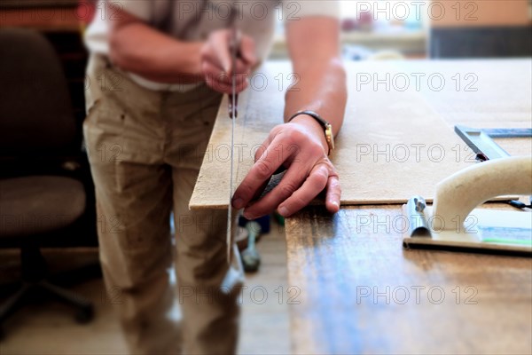 Midsection of Caucasian man cutting panel with saw