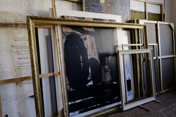 Paintings and frames leaning on wall