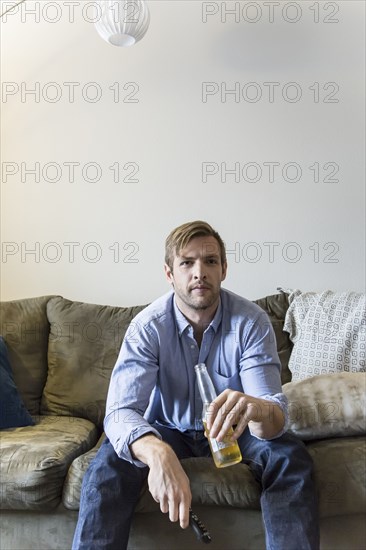 Man drinking beer on sofa