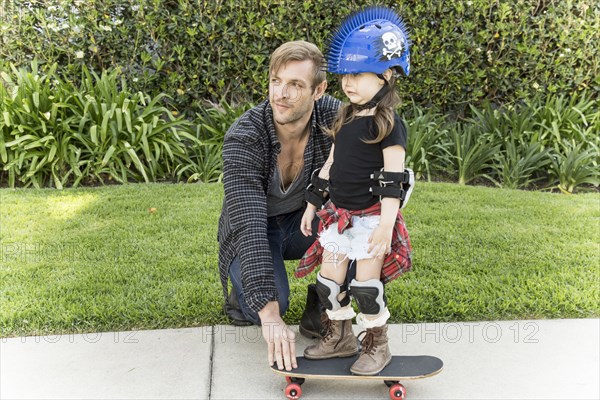 Father teaching daughter to skateboard