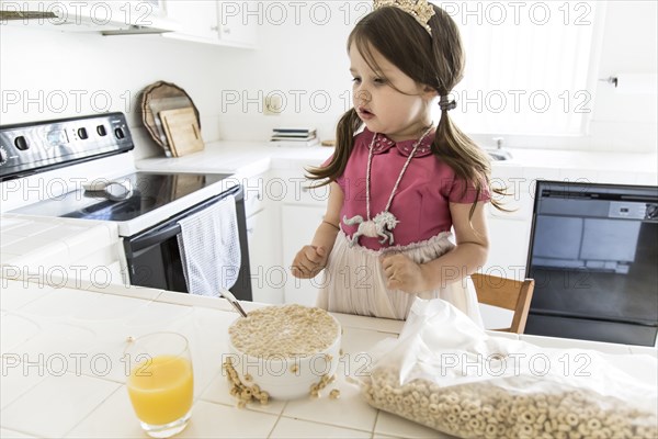 Caucasian girl eating cereal in kitchen