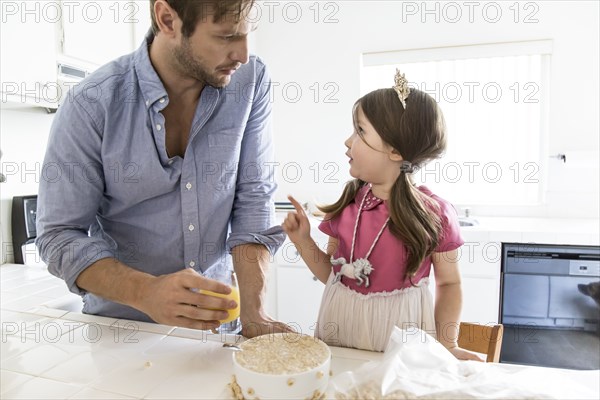 Caucasian father and daughter eating cereal in kitchen