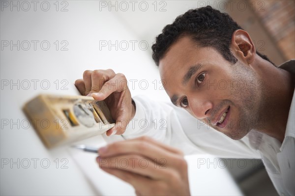 Hispanic carpenter using level on wall