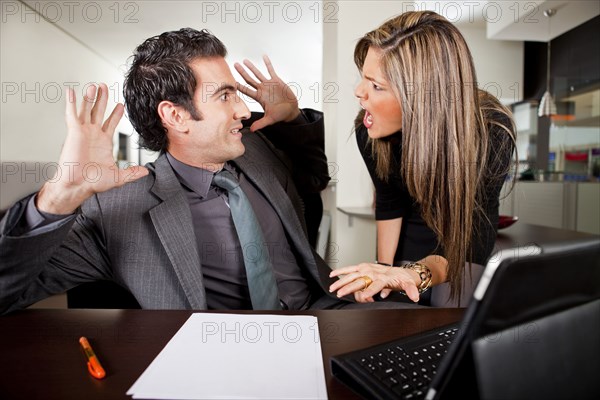Hispanic businesswoman shouting at co-worker in office