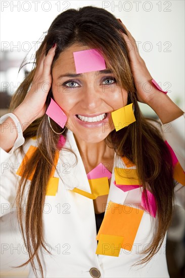 Hispanic businesswoman covered in sticky notes