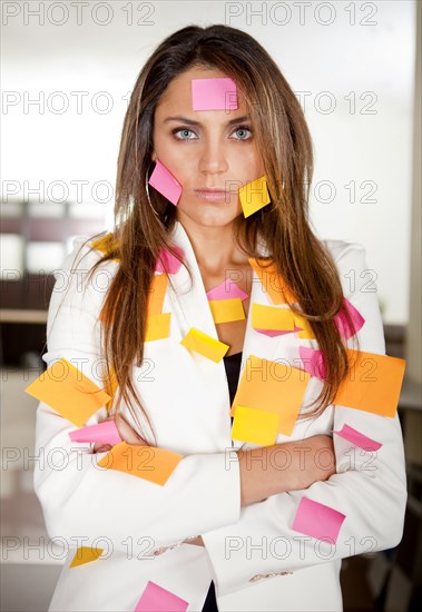 Hispanic businesswoman covered in sticky notes