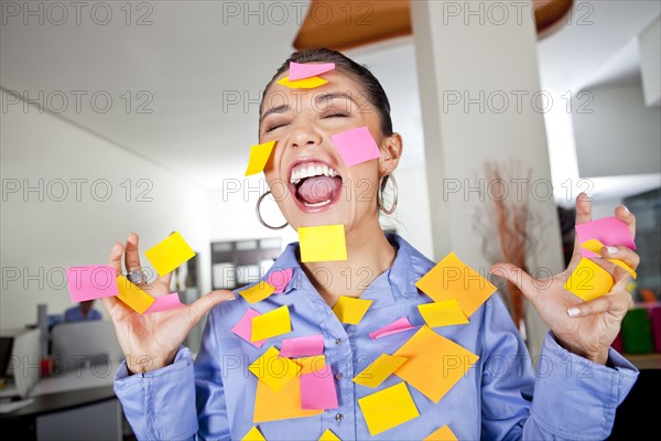 Hispanic businesswoman covered in sticky notes