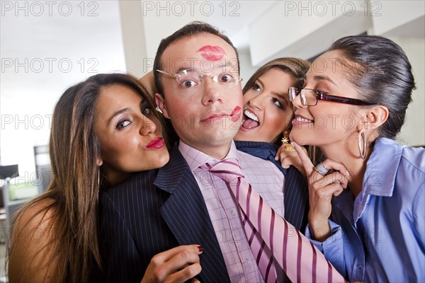 Businesswomen kissing male co-worker