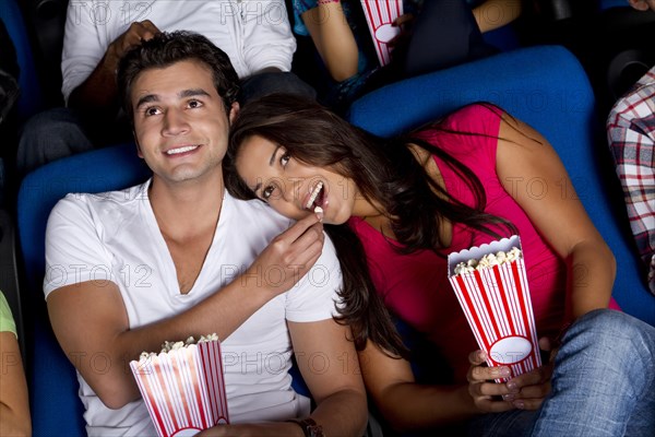 Hispanic couple enjoying popcorn at movie theater
