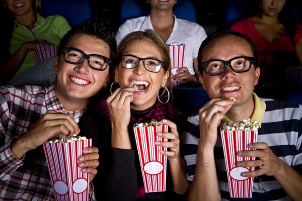 Hispanic friends enjoying popcorn at movie theater