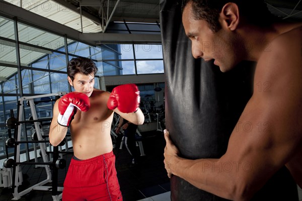 Hispanic man using punching bag in health club