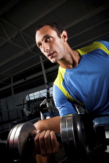 Hispanic man lifting weights in health club