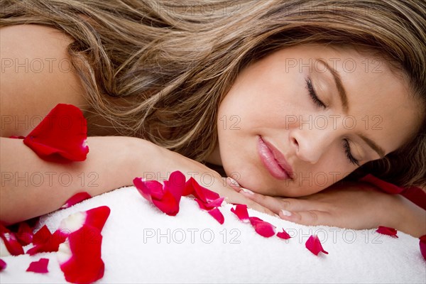 Hispanic woman laying on massage table covered in rose petals