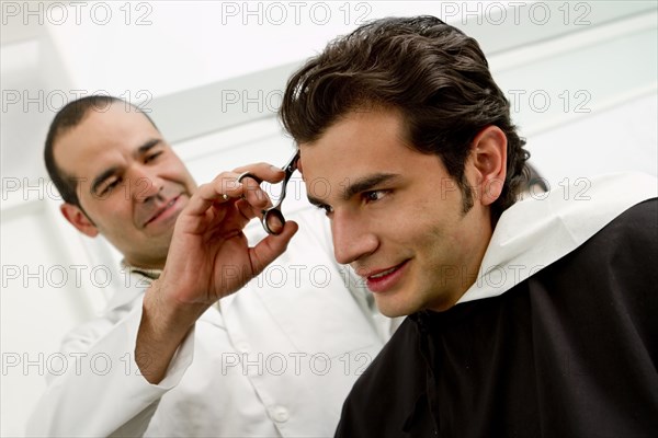 Hispanic man having hair cut in barber shop