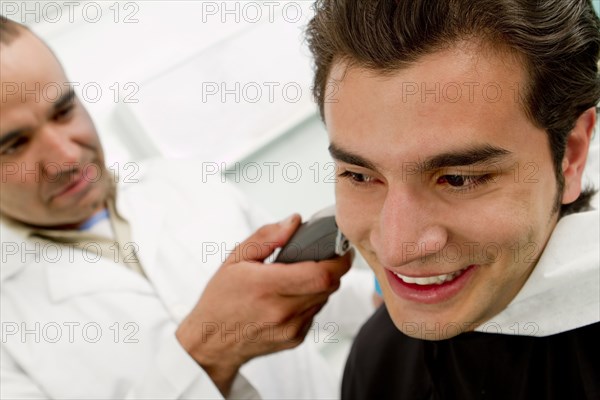 Hispanic Barber shaving man's neck in barber shop